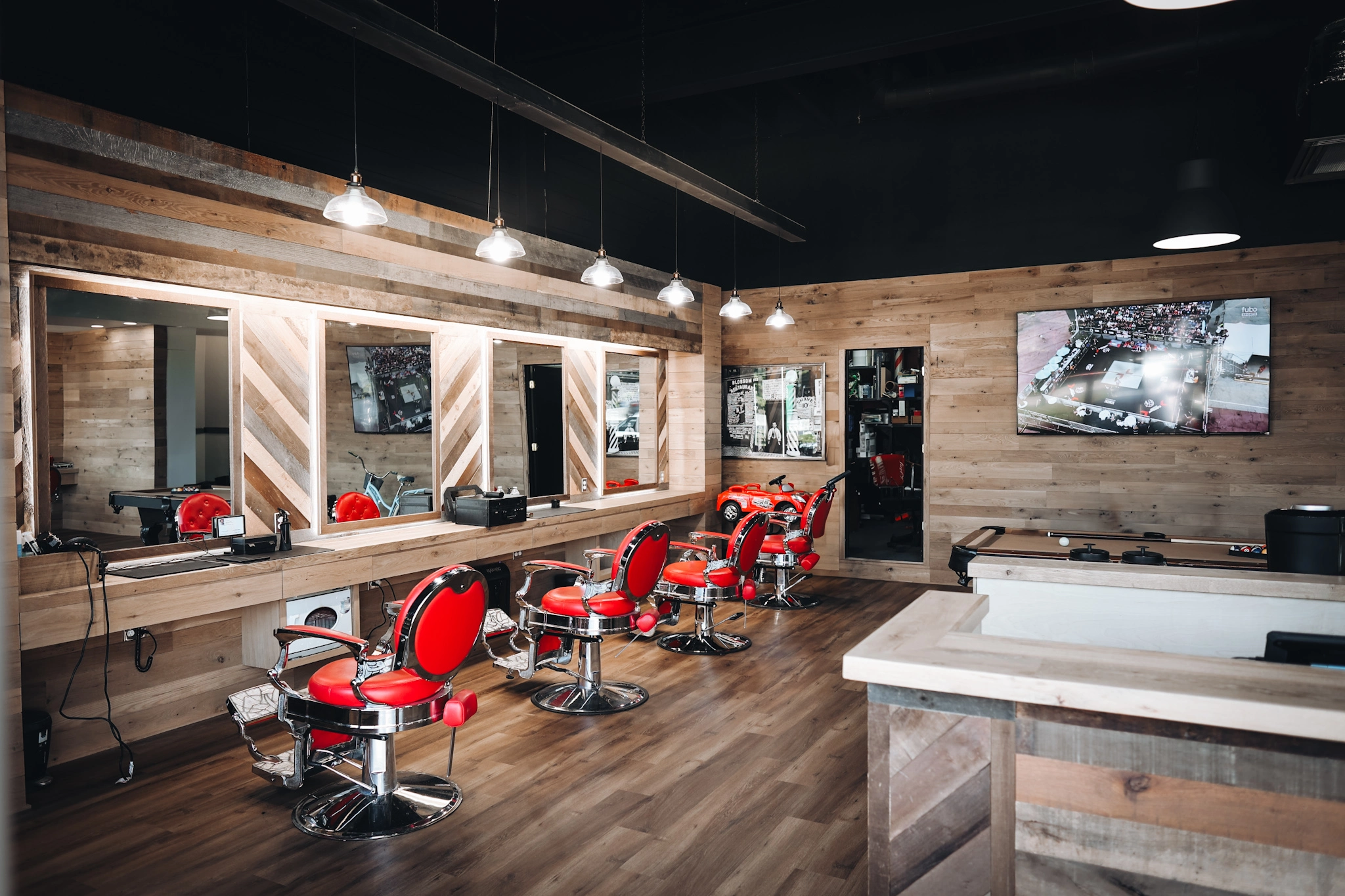 Modern barbershop interior with red chairs and wood paneling